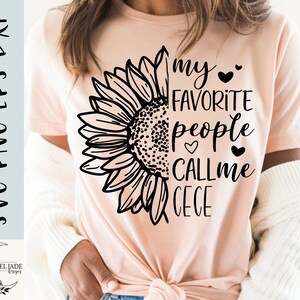 May include: A pink t-shirt with a black sunflower graphic and the text "my favorite people call me Cece".