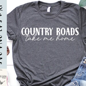 May include: A gray t-shirt with the text "COUNTRY ROADS take me home" in white lettering.