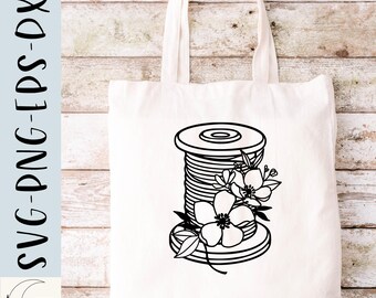 May include: A black and white line drawing of a spool of thread with flowers on top. The spool is on a white tote bag.