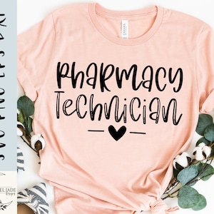 May include: A pink t-shirt with the text "Pharmacy Technician" in black script font. A small black heart is centered below the text.