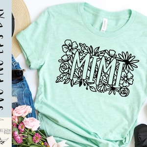 May include: A light green t-shirt with the word "MIMI" in black outlined letters surrounded by black floral designs.