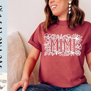 May include: A maroon t-shirt with a white floral design and the word "MIMI" in the center.