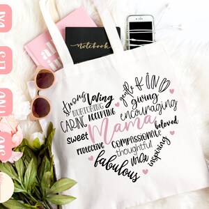 Puede incluir: Una bolsa de tela blanca con un dise&ntilde;o de coraz&oacute;n rosa y la palabra "Mama" en el centro. El coraz&oacute;n est&aacute; rodeado de palabras que describen a una madre, como "fuerte", "cari&ntilde;osa", "cuidadosa", "amable", "bondadosa", "generosa", "alentadora", "dulce", "protectora", "compasiva", "pensativa", "sabia", "inspiradora", "fabulosa" y "amada".