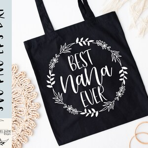 May include: Black tote bag with white text that reads "Best Nana Ever" surrounded by a floral wreath.