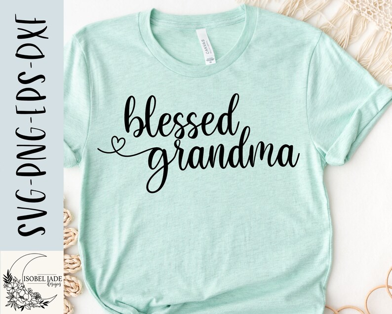 May include: A light blue t-shirt with the text "blessed grandma" in black cursive lettering. A small heart is above the word "grandma".