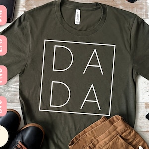 Op de afbeelding: Een groen T-shirt met een wit vierkant ontwerp met de tekst "DA DA" in blokletters.