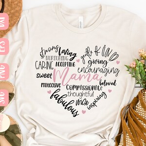 Puede incluir: Una camiseta blanca con un dise&ntilde;o de coraz&oacute;n rosa. El coraz&oacute;n est&aacute; lleno de palabras que describen a una madre, incluyendo "fuerte", "cari&ntilde;osa", "amable", "bondadosa", "cari&ntilde;osa", "aceptante", "generosa", "alentadora", "dulce", "protectora", "compasiva", "pensativa", "sabia", "inspiradora" y "fabulosa".
