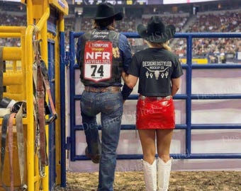 Mockup da camiseta cropped preta Comfort Colors 3023CL, vista traseira, cenário da arena do Rodeio NFR em Las Vegas, estilo autêntico de cowgirl do Oeste americano.