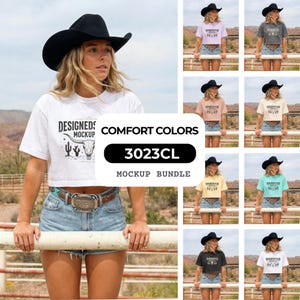 May include: A mockup bundle of Comfort Colors t-shirts in various pastel shades. The shirts feature a desert-themed graphic and the text "DESIGNED MOCKUP". The model is wearing a black cowboy hat and denim shorts. The bundle includes the code 3023CL.