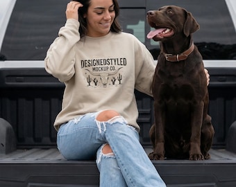 Mockup de moletom Gildan 18000 Sand Crewneck, cena country com cachorro na traseira de uma caminhonete, foto de vestuário com vista frontal para estilo de vida rural do Oeste americano.