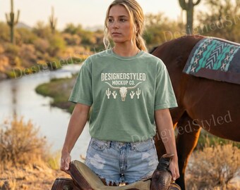Mockup da camiseta Comfort Colors 1717 Bay, modelo feminina com sela, manta Desert River Aztec, foto de estilo de vida equestre de cowgirl do oeste americano.