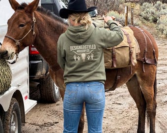 Maqueta de sudadera con capucha Gildan 18500 verde militar (vista posterior), vida en un rancho del oeste, foto de sudadera con capucha con estética ecuestre en un sendero de montaña