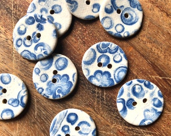Könnte beinhalten: Zehn runde, blaue und weiße Keramikknöpfe mit einem Blumenmuster. Die Knöpfe haben jeweils zwei Löcher.