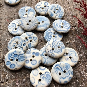May include: A collection of ceramic buttons with a blue and white floral pattern. The buttons are round and have two holes.