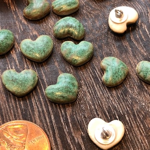 Puede incluir: Surtido de botones de cerámica en forma de corazón verde y blanco con un esmalte moteado.