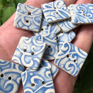 Peut inclure: Un ensemble de boutons en céramique bleu et blanc avec un motif en spirale. Les boutons sont de forme carrée et ont deux trous chacun.