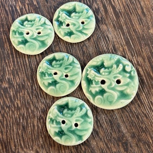 Op de afbeelding: Vijf groene keramische knopen met een drakenontwerp. De knopen hebben elk twee gaten.