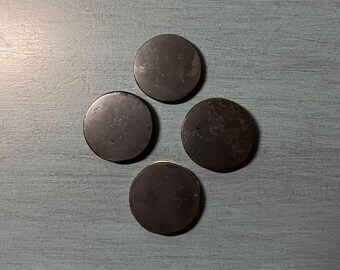May include: Four black round coasters on a blue textured surface.