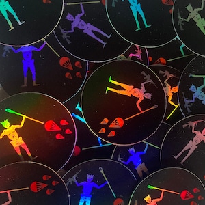 May include: A collection of round, holographic stickers featuring a skeleton figure with a crown, holding a spear and a rifle. The design includes a parachute and blood drops, set against a black background.