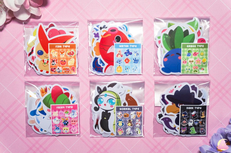 May include: Six clear plastic bags each containing a set of colorful cartoon stickers. Each bag has a different Pokemon type: Fire, Water, Grass, Fairy, Normal, and Dark. Each set includes a larger sticker of a Pokemon and a smaller sheet of stickers with various Pokemon of that type.