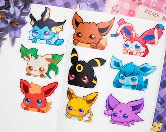 May include: Nine colorful cartoon stickers featuring different Pokemon characters. The stickers are on a white background. The characters include Eevee, Vaporeon, Jolteon, Flareon, Espeon, Umbreon, Leafeon, Glaceon, and Sylveon.
