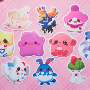 May include: A set of nine colorful cartoon character stickers featuring various Pokemon characters. The stickers are printed on white paper and have a glossy finish.