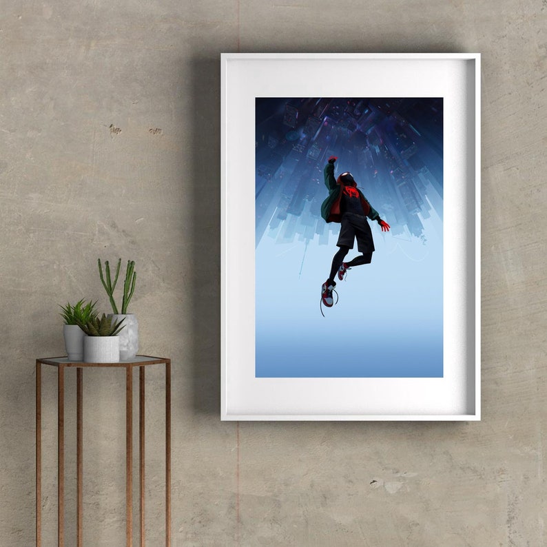 May include: A framed poster featuring a stylized illustration of a superhero in a red and black suit, with a green jacket, jumping in front of a city skyline. The city is upside down, with the sky in the background.