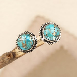 Puede incluir: Un par de pendientes de botón redondos con incrustaciones de piedra turquesa y dorada. Los pendientes están engarzados en un metal plateado con un diseño de cuerda trenzada. El texto "925 Artisan Jewelry" es visible.