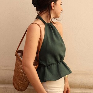 Peut inclure: Une femme portant un haut halter vert fonc&eacute; avec une jupe blanche et un sac en osier brun.