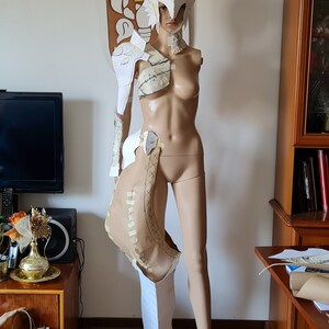 Puede incluir: Un traje de armadura de papel blanco para cosplay, con casco, hombreras y armadura de pierna. La armadura se est&aacute; ensamblando en un maniqu&iacute;.