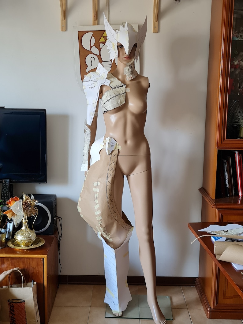 Puede incluir: Un traje de armadura de papel blanco para cosplay, con casco, hombreras y armadura de pierna. La armadura se est&aacute; ensamblando en un maniqu&iacute;.