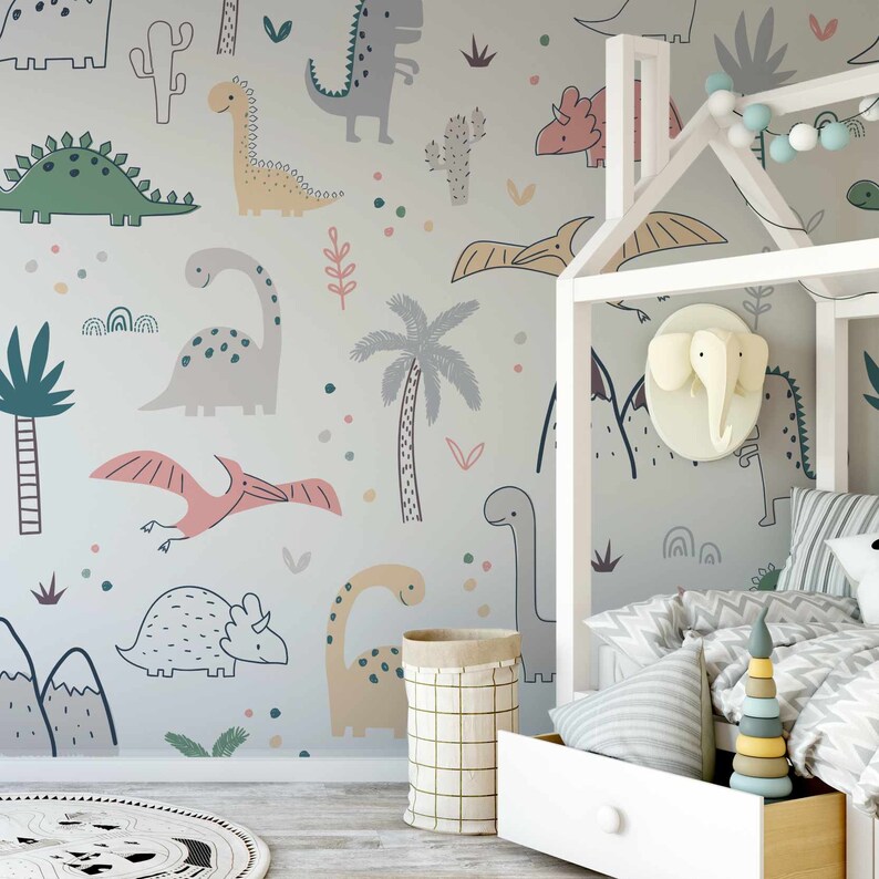 May include: A light gray nursery wall mural with a dinosaur theme. The mural features various dinosaurs, including a green stegosaurus, a pink pterodactyl, and a yellow brachiosaurus. There are also palm trees, cacti, and other plants on the mural.
