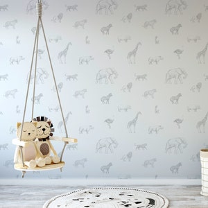 May include: A light blue wall with a white and gray animal print wallpaper. A white swing with two stuffed animal lions is hanging from the ceiling. A black and white rug is on the floor.