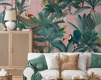 May include: A pink and white wallpaper with a jungle theme. The wallpaper features zebras, toucans, peacocks, leopards, and tropical plants. The wallpaper is shown in a living room setting with a white couch, green throw pillows, and a wooden cabinet.