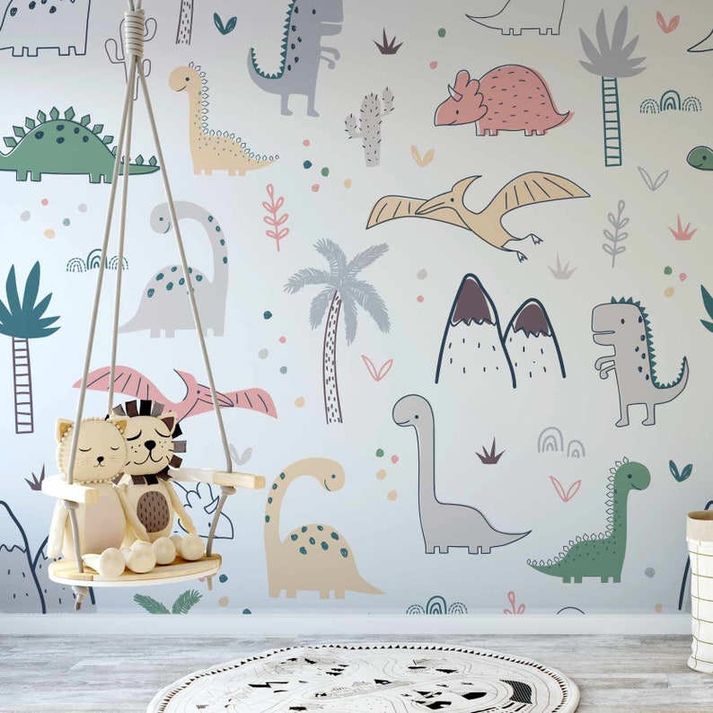 May include: A white wall with a dinosaur themed wallpaper featuring various dinosaurs in different colors and poses, including green, pink, yellow, and gray. There are also palm trees, mountains, and other jungle-themed elements. A wooden swing with two stuffed animals is hanging in front of the wall.