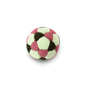 Puede incluir: Una pequeña pelota redonda multicolor con un patrón geométrico. La pelota está compuesta por formas variadas en tonos de rosa, marrón y verde claro. La pelota está hecha de un material suave y es adecuada para jugar.