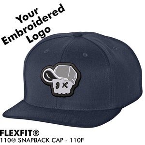 Peut inclure: Une casquette Flexfit 110 Snapback de couleur bleu marine avec un motif de crâne brodé en gris et noir. La casquette a une visière incurvée et une sangle réglable.