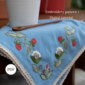Könnte beinhalten: Ein blaues Leinen-Geschirrtuch mit weißer Häkelborte und gestickten Erdbeeren und Blumen. Der Text "Embroidery pattern + Digital tutorial" und "PDF" ist sichtbar.