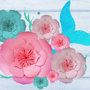 May include: A mermaid tail cutout with glitter, surrounded by pink and teal paper flowers. The flowers are layered and have a 3D effect.