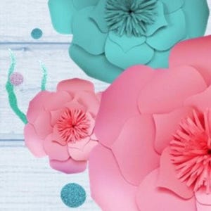 May include: Three large paper flowers, one teal blue and two pink, with a wood background. The flowers are layered and have a ruffled appearance.