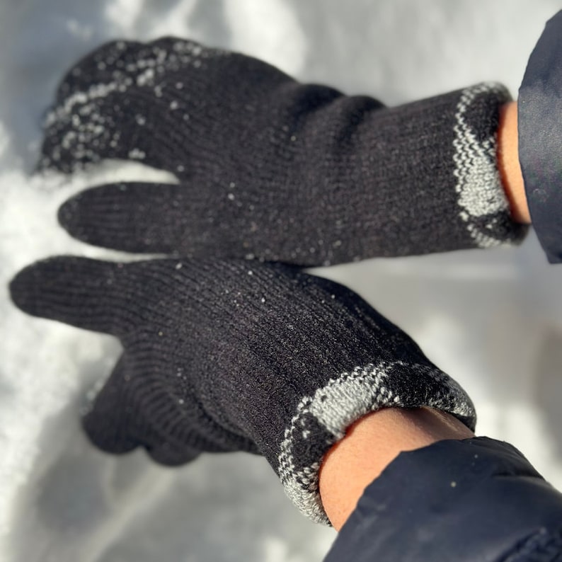 May include: A pair of black knit gloves with gray trim. The gloves are worn and have a textured surface.