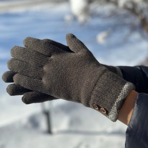 May include: A pair of brown knit gloves with a white trim and two brown buttons on the cuff.