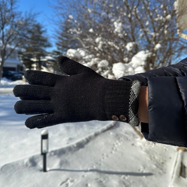 May include: Black knit gloves with a plaid cuff and two brown buttons.