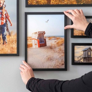 Black 17 piece gallery wall frame set with different size picture frames arranged on a modern living room wall.