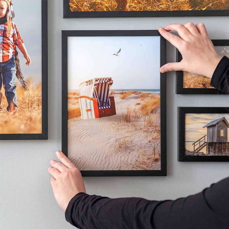 Black 17 piece gallery wall frame set with different size picture frames arranged on a modern living room wall.