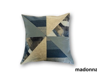 Könnte beinhalten: Ein dekoratives Kissen mit einem geometrischen Muster in Blautönen, Braun und Beige. Das Kissen ist aus einem weichen, strukturierten Stoff gefertigt.