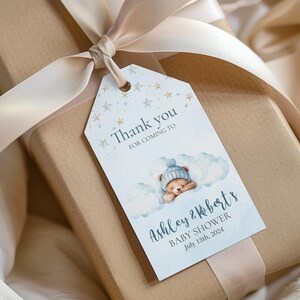 Puede incluir: Etiqueta de agradecimiento para una fiesta de bienvenida al bebé azul y blanca con un oso de peluche durmiendo en una nube, estrellas y el texto "Gracias por venir a la fiesta de bienvenida al bebé de Ashley & Robert el 13 de julio de 2024".