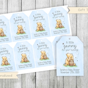 Pu&ograve; includere: Un set di otto etichette regalo per una baby shower a tema Winnie the Pooh. Ogni etichetta presenta un'illustrazione a fumetti di Winnie the Pooh che tiene un barattolo di miele. Le etichette sono stampate su cartoncino bianco con sfondo blu e il testo "Un po' buono per la tua pancia!" e "Baby Shower di Sandra 27 novembre 2020".
