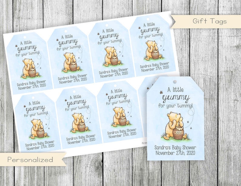 Pu&ograve; includere: Un set di otto etichette regalo per una baby shower a tema Winnie the Pooh. Ogni etichetta presenta un'illustrazione a fumetti di Winnie the Pooh che tiene un barattolo di miele. Le etichette sono stampate su cartoncino bianco con sfondo blu e il testo "Un po' buono per la tua pancia!" e "Baby Shower di Sandra 27 novembre 2020".