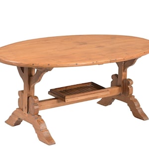 May include: An oval wooden coffee table with a light brown finish, featuring a smooth tabletop surface and a lower slatted shelf. The table is supported by two sturdy trestle-style legs with curved decorative cutouts at the base.
